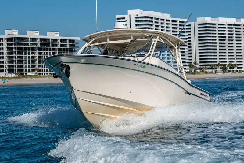 Slide: The Image of 2013 Grady-White 335 boat cruising on water with modern buildings in the background. - 27