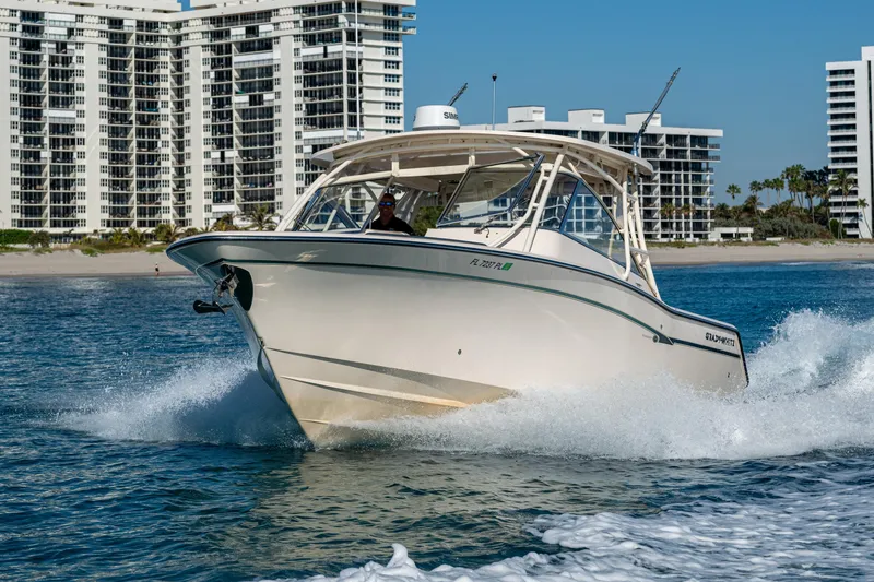 Slide: The Image of 2013 Grady-White 335 boat cruising near modern beachfront buildings. - 28