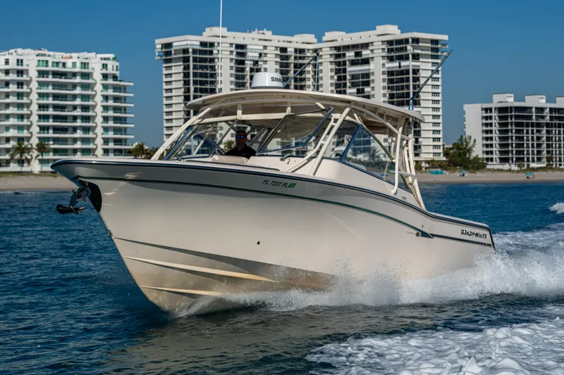Slide: The Image of 2013 Grady-White 335 boat cruising near modern waterfront buildings. - 29