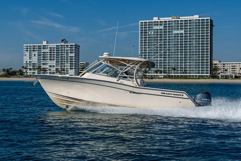 Slide: The Image of 2013 Grady-White 335 boat cruising near modern beachfront buildings. - 32