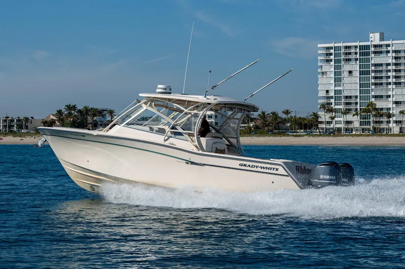 Slide: The Image of 2013 Grady-White 335 boat cruising on water near a coastal cityscape. - 34