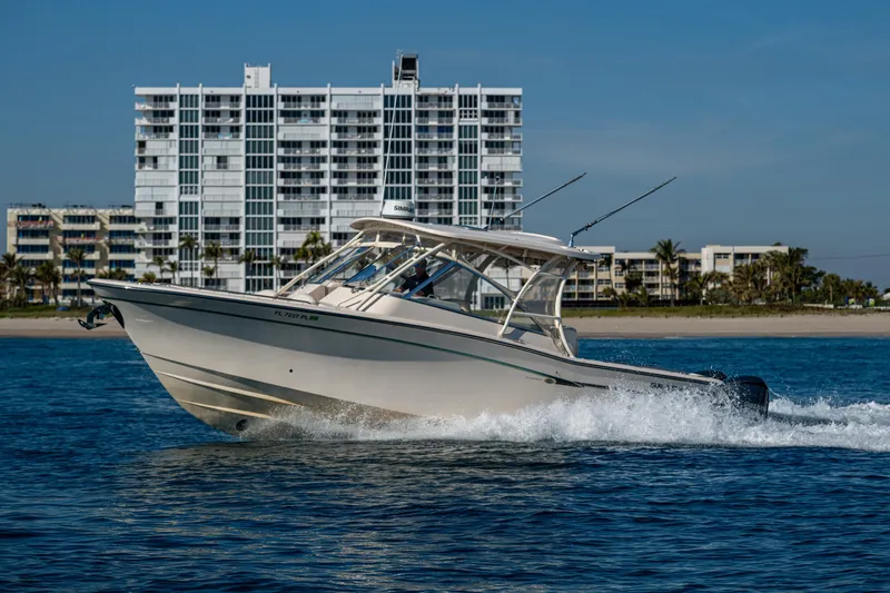 Slide: The Image of 2013 Grady-White 335 boat cruising near modern waterfront buildings. - 35