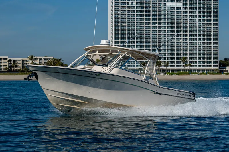 Slide: The Image of 2013 Grady-White 335 boat cruising on water with a cityscape backdrop. - 36