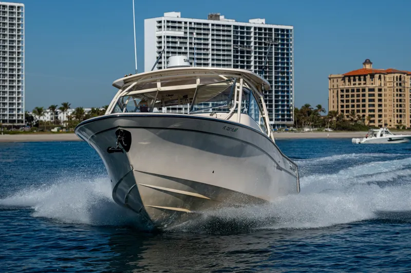Slide: The Image of 2013 Grady-White 335 boat cruising near modern beachfront buildings. - 38