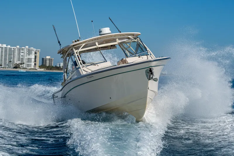 Slide: The Image of 2013 Grady-White 335 boat cruising on open water with city skyline in background. - 40