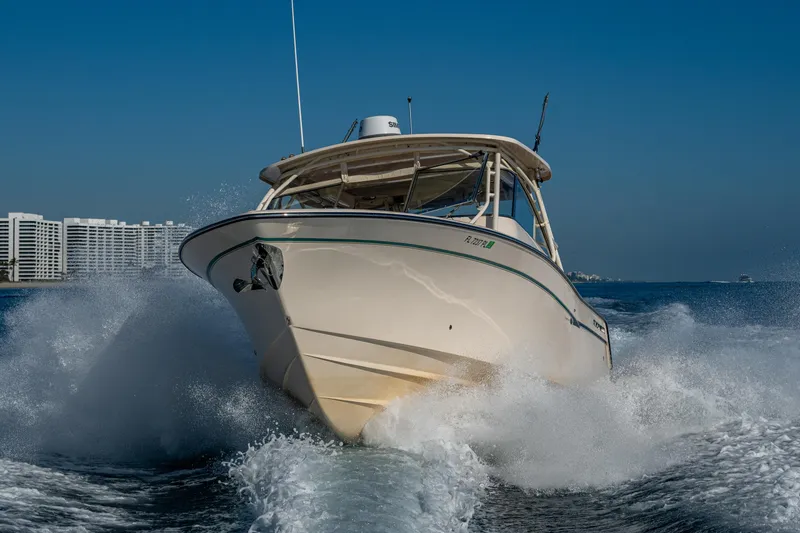 Slide: The Image of 2013 Grady-White 335 boat cruising on open water with cityscape background. - 46