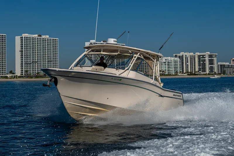 Slide: The Image of 2013 Grady-White 335 boat cruising on water with city skyline in background. - 47