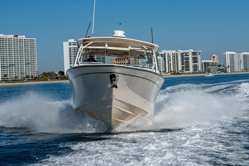 Slide: The Image of 2013 Grady-White 335 boat cruising on water with city skyline in background. - 49
