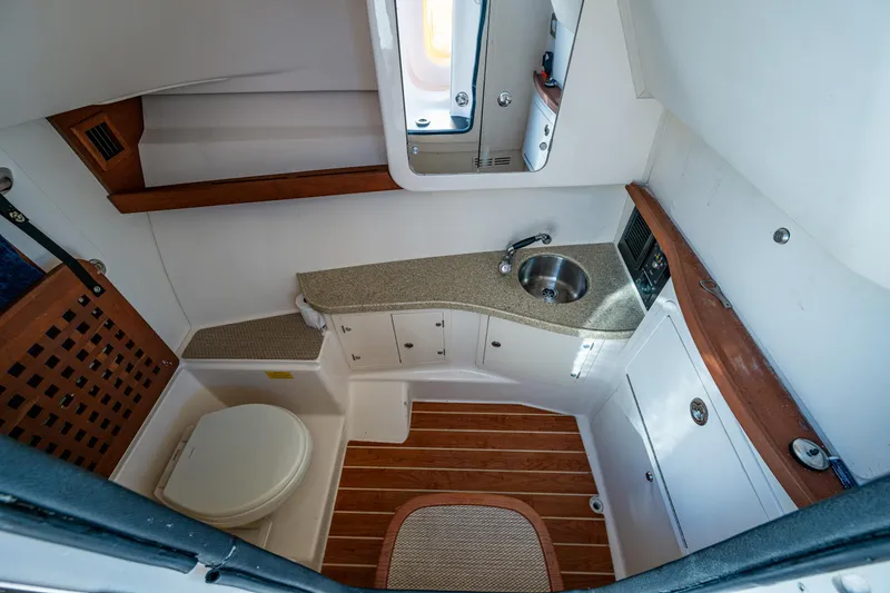 Slide: The Image of 2013 Grady-White 335 boat interior with compact bathroom, sink, and wooden accents. - 6