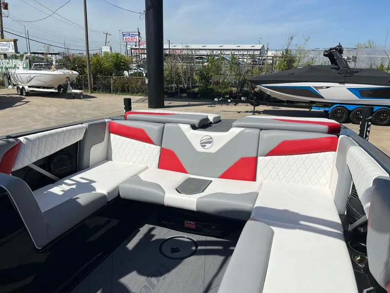 Slide: The Image of 2024 Tigé Z3 boat interior with red and gray seating, parked outdoors. - 14
