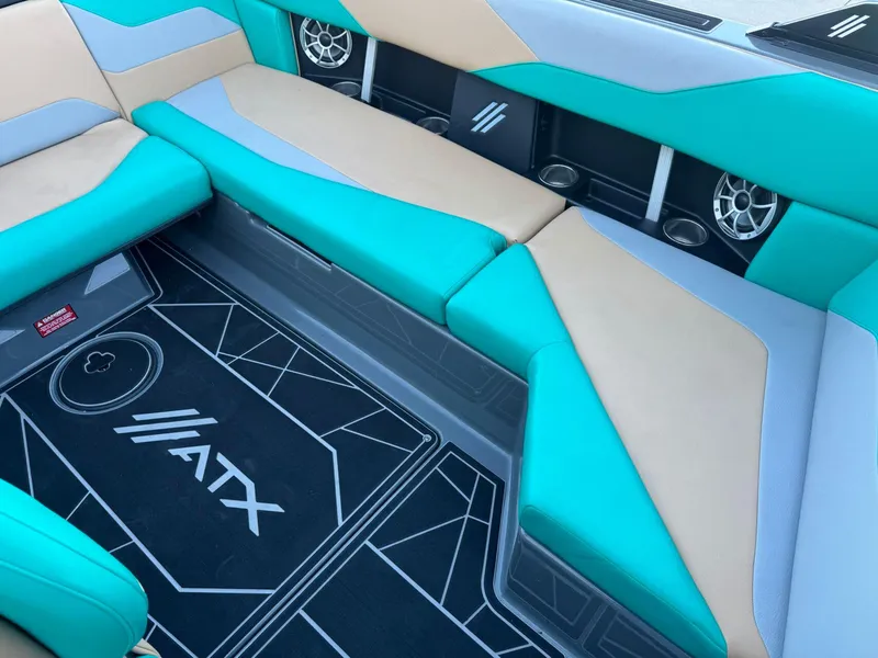 Slide: The Image of 2023 ATX Surf Boats 20 Type-S interior with teal and beige seating, featuring cup holders and speakers. - 14