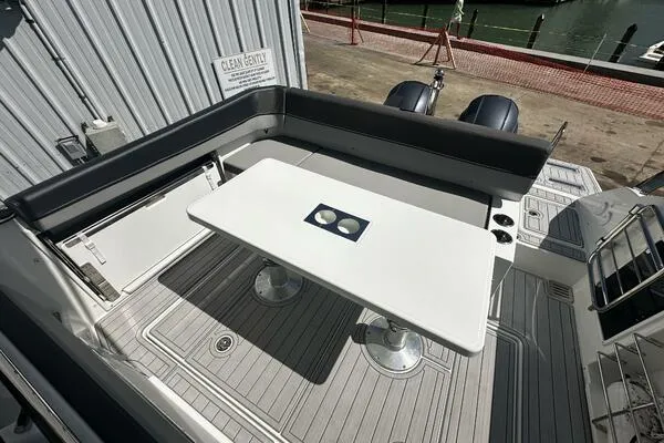 Slide: The Image of 2024 Jeanneau Leader 9.0 WA boat deck with seating and table, docked at marina. - 29