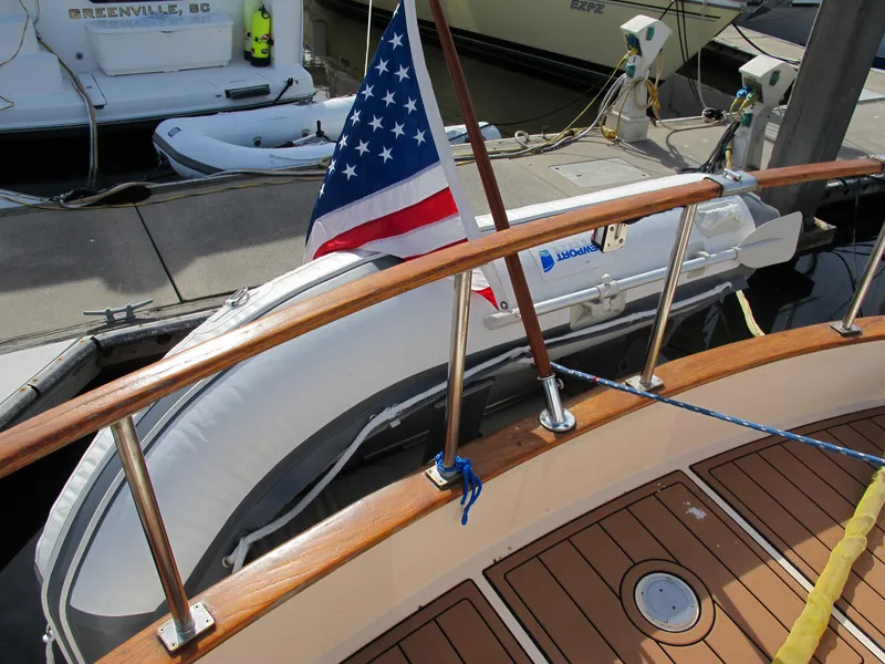 Slide: The Image of 1984 Monk 36 boat with American flag, docked with inflatable dinghy. - 15