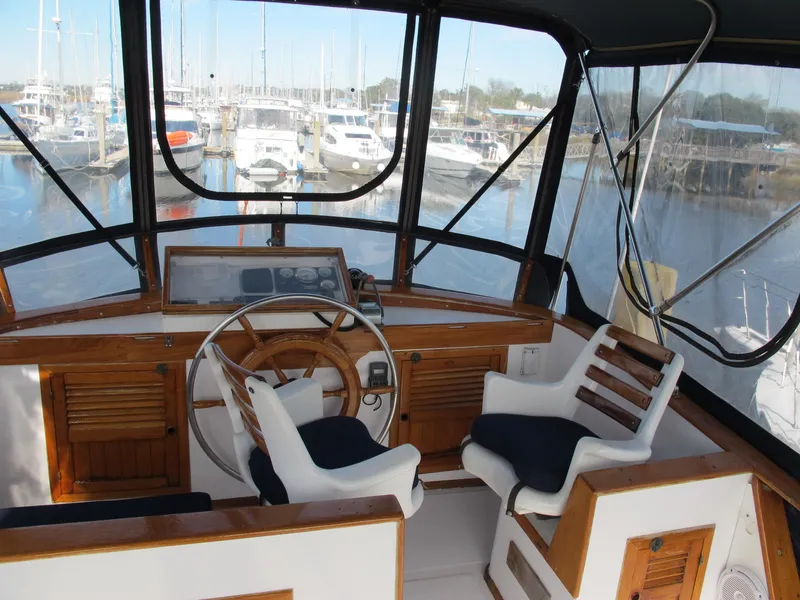 Slide: The Image of 1984 Monk 36 boat interior with steering wheel and marina view. - 23