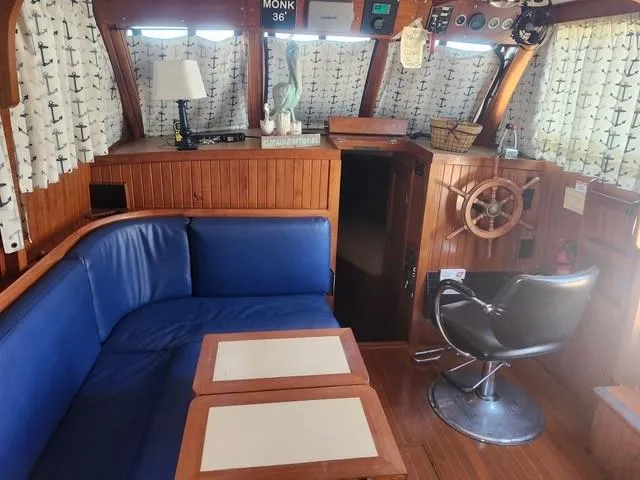 Slide: The Image of Cozy 1984 Monk 36 boat interior with blue seating, wooden helm, and nautical decor. - 30