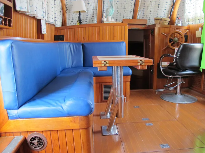 Slide: The Image of 1984 Monk 36 boat interior with blue seating, wooden table, and steering wheel. - 37
