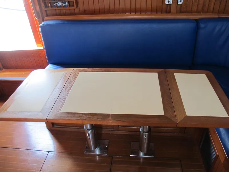 Slide: The Image of Wooden table with blue seating in a 1984 Monk 36 boat interior. - 38