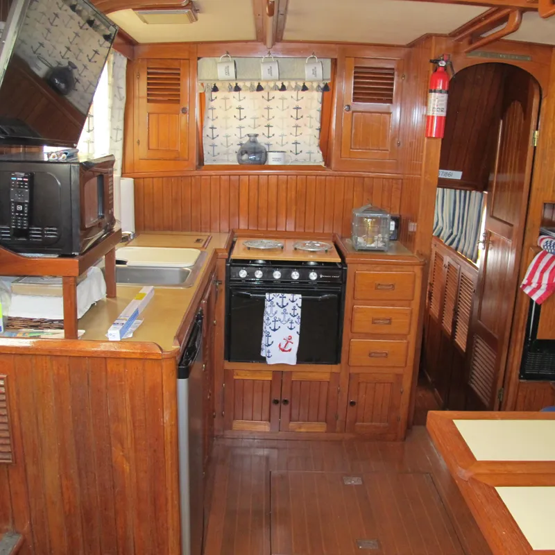 Slide: The Image of Wooden interior of a 1984 Monk 36 boat kitchen with stove and microwave. - 41
