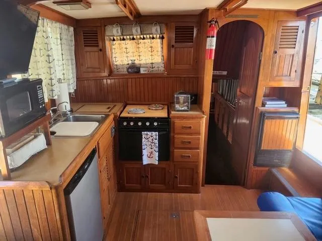 Slide: The Image of 1984 Monk 36 boat interior with wooden kitchen, appliances, and nautical decor. - 42
