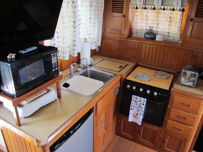 Slide: The Image of 1984 Monk 36 yacht kitchen with microwave, stove, and nautical-themed decor. - 43