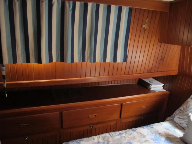 Slide: The Image of Wood-paneled cabin interior of 1984 Monk 36 boat with striped curtains and storage drawers. - 54
