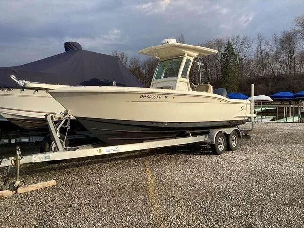 Slide: The Image of 2013 Scout 245 XFS boat on trailer, parked outdoors on gravel. - 3