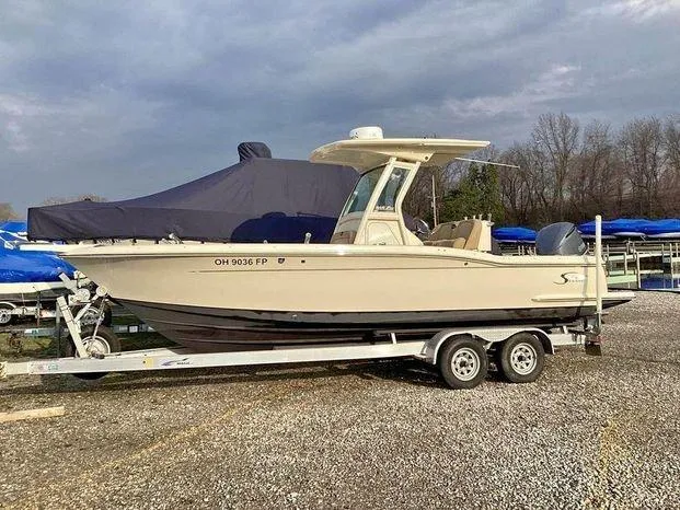 Slide: The Image of 2013 Scout 245 XFS boat on trailer, parked outdoors, overcast sky. - 7
