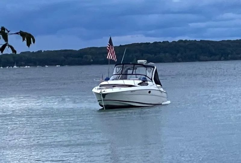 Slide: The Image of 2008 Regal 3360 Window Express boat on a lake with American flag. - 2
