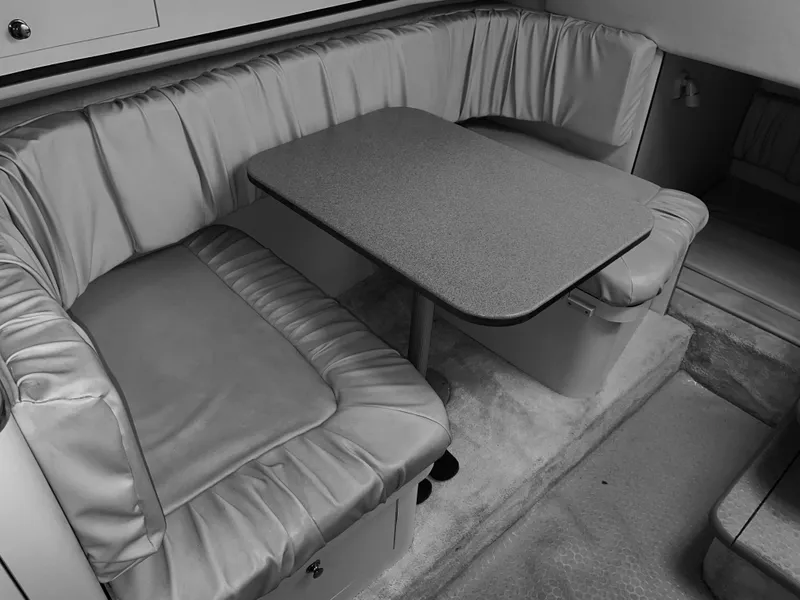 Slide: The Image of 2000 Sea Ray 290 Amberjack interior with cushioned seating and table. - 25