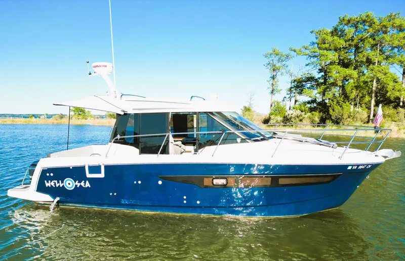 Slide: The Image of 2021 Jeanneau NC 895 boat on a calm lake with trees in the background. - 1