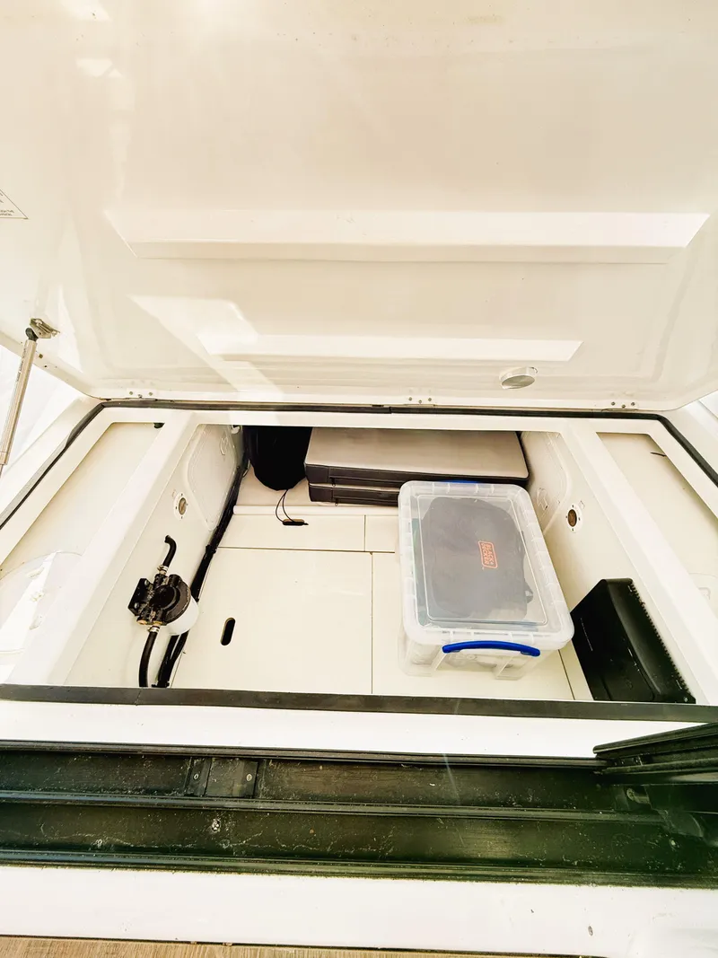 Slide: The Image of 2021 Jeanneau NC 895 storage compartment with plastic container inside. - 12