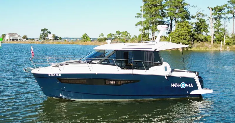 Slide: The Image of 2021 Jeanneau NC 895 boat on a serene lake with trees in the background. - 3