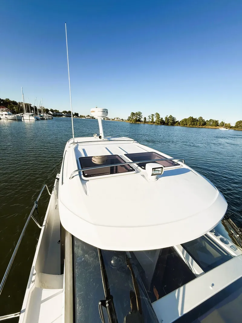 Slide: The Image of 2021 Jeanneau NC 895 boat cruising on a calm river under clear blue skies. - 8