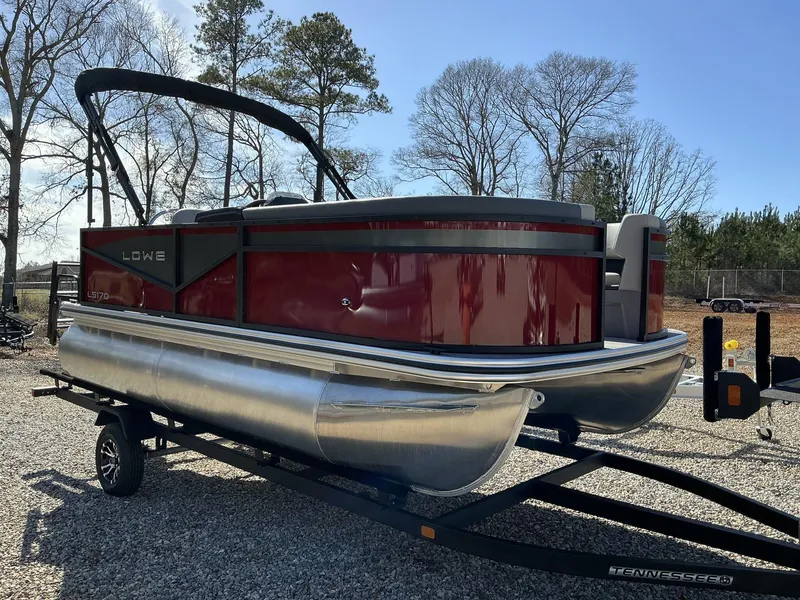 Slide: The Image of 2025 Lowe LS 170 pontoon boat on trailer, parked outdoors. - 1