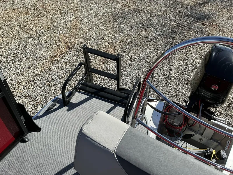 Slide: The Image of 2025 Lowe LS 170 boat deck with motor and seating, on gravel surface. - 11