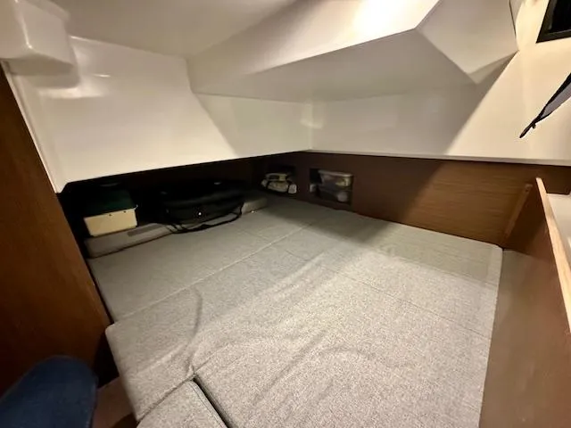 Slide: The Image of 2019 Beneteau Antares 27 cabin interior with gray bedding and wooden accents. - 10
