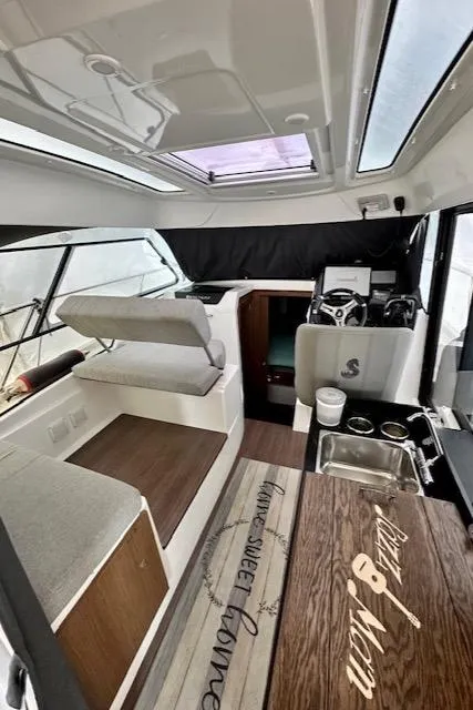 Slide: The Image of Interior of a 2019 Beneteau Antares 27 boat, featuring seating, helm, and kitchenette. - 15