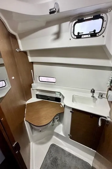 Slide: The Image of 2019 Beneteau Antares 27 boat interior with compact bathroom and wooden accents. - 23