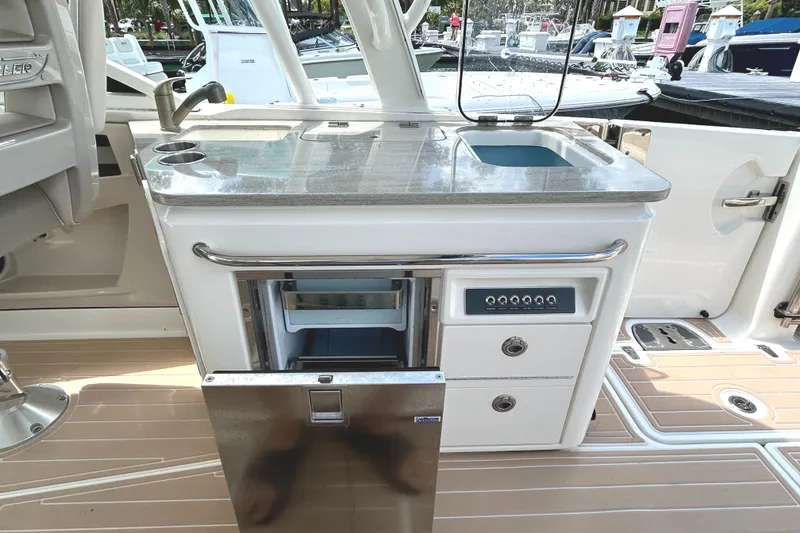 Slide: The Image of Boston Whaler 320 Vantage 2017 boat kitchenette with sink, fridge, and storage drawers. - 25