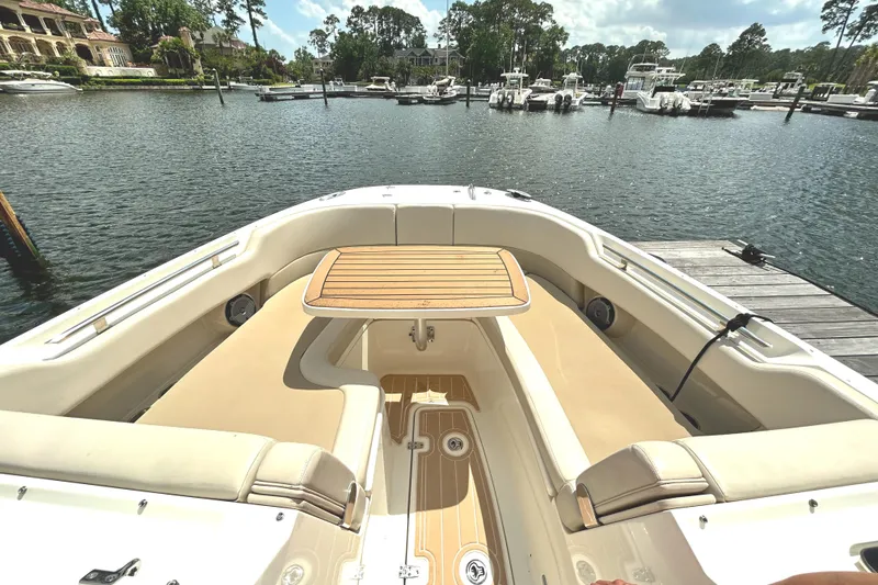 Slide: The Image of 2017 Boston Whaler 320 Vantage boat interior with seating and table, docked by a marina. - 30