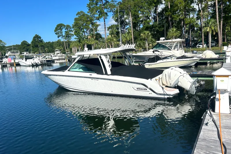 Slide: The Image of 2017 Boston Whaler 320 Vantage boat docked in a serene marina setting. - 5