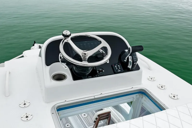 Slide: The Image of 2022 Barker Boatworks 26 Open helm with steering wheel and controls on calm water. - 28