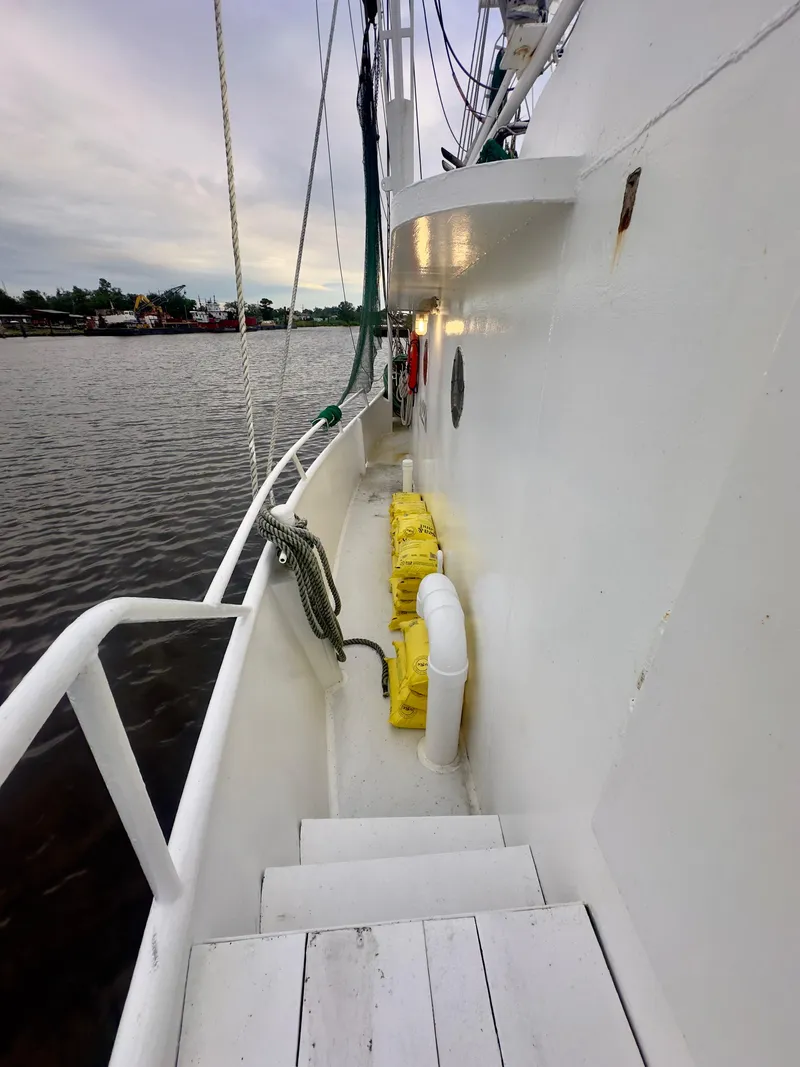 Slide: The Image of 2001 Blanchard 69 Shrimper/Freezer boat deck with safety equipment, docked by calm waters. - 32