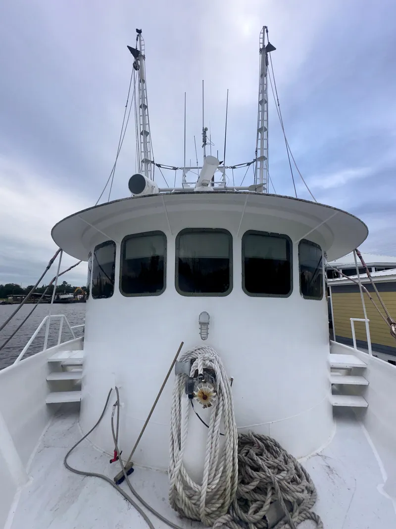 Slide: The Image of 2001 Blanchard 69 Shrimper/Freezer boat with ropes on deck, docked under cloudy sky. - 34