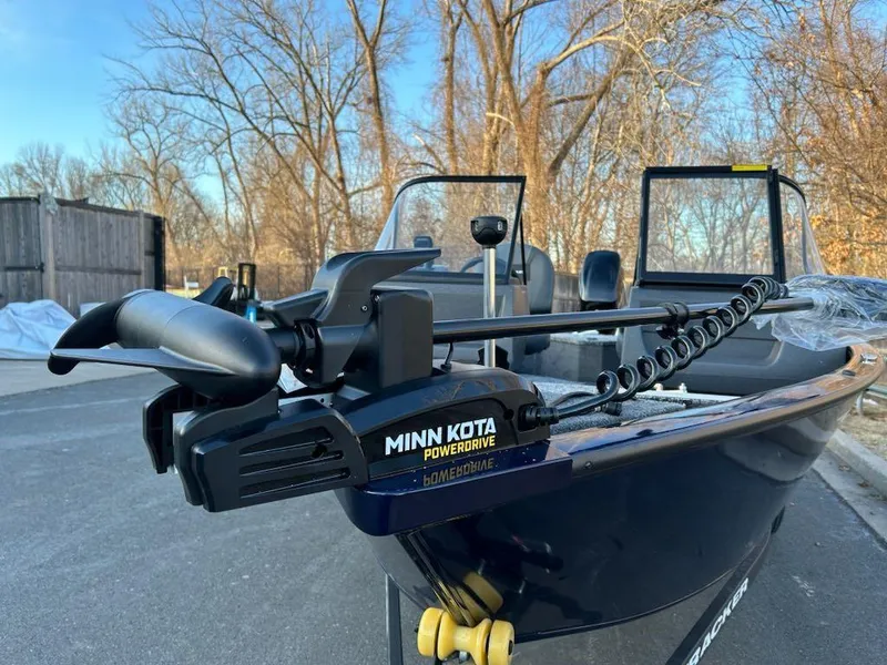 Slide: The Image of 2025 Tracker Pro Guide V-16 WT boat with Minn Kota PowerDrive motor in a wooded area. - 2
