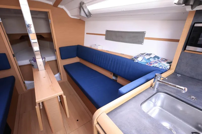 Slide: The Image of Interior of 2021 Jeanneau Sun Odyssey 349 sailboat with blue seating and compact kitchen area. - 15