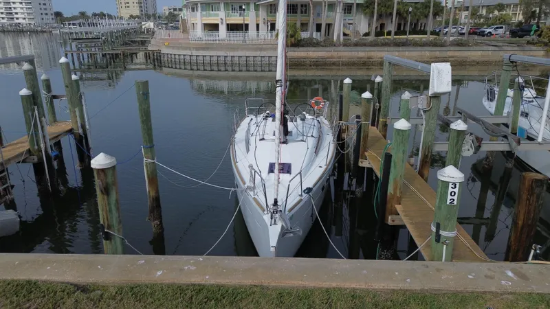 Slide: The Image of 2021 Jeanneau Sun Odyssey 349 docked at a marina, surrounded by pilings and calm water. - 6