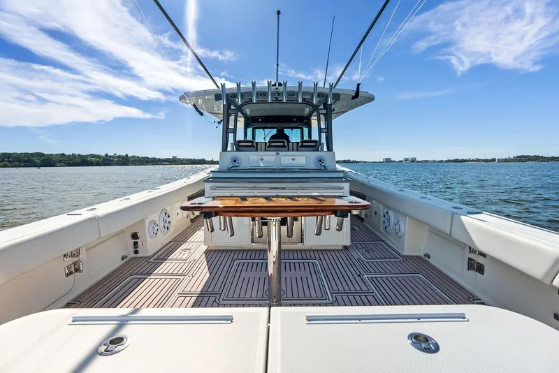 Slide: The Image of 2018 HCB 53 Sueños boat on water, featuring spacious deck and clear blue sky. - 17