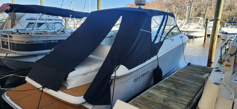 Slide: The Image of 2010 Cobalt 323 boat docked with black canopy, surrounded by other boats. - 0