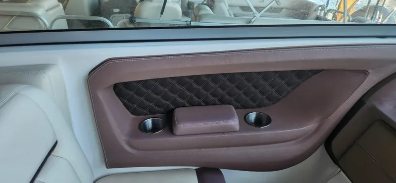 Slide: The Image of Interior of a 2010 Cobalt 323 boat, featuring brown leather paneling and cup holders. - 11